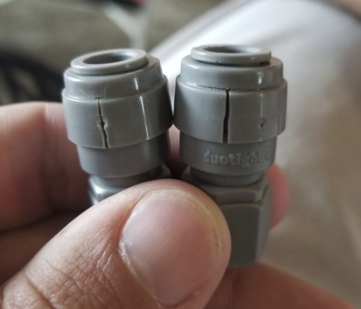 Two Gen 1 DuoTight fittings showing vertical ESC cracks through the POM collar